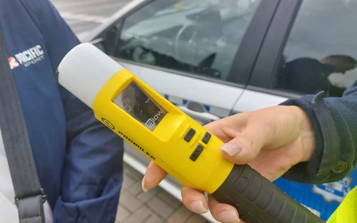 Policjant z alkomatem bada trzeźwość kierowcy